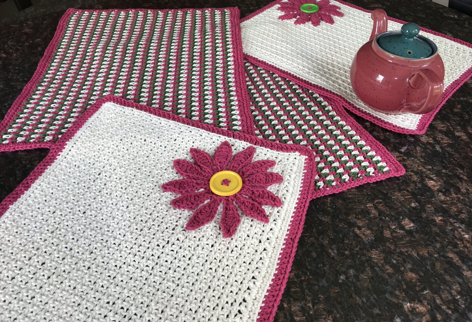 Crocheted placemats in red, green, and white with a tea pot
