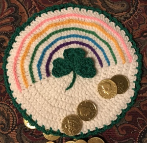 Crochet circular hot pad with a rainbow and shamrock on it